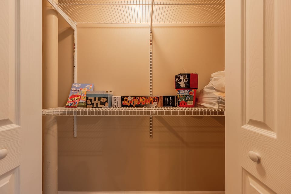 Fully stocked game closet with puzzles, board games, and extra blankets.