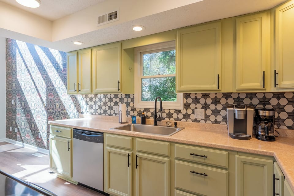 Fully equipped kitchen with bold backsplash, stainless appliances, and coffee station.
