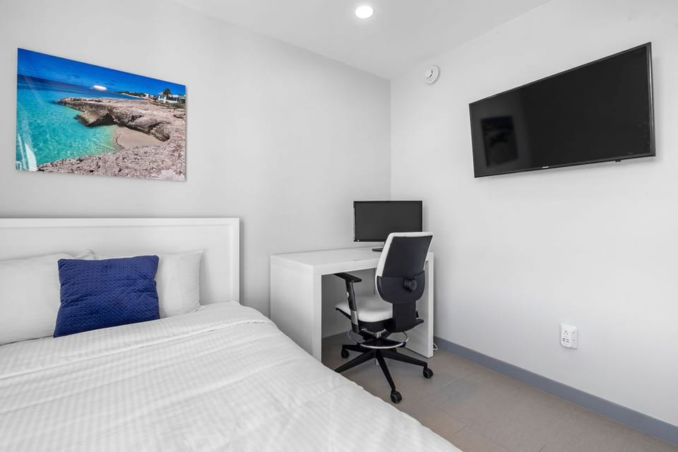 Your peaceful bedroom combines rest and productivity with a cozy bed, dedicated workspace, and wall-mounted TV—perfect for unwinding after exploring nearby beaches.