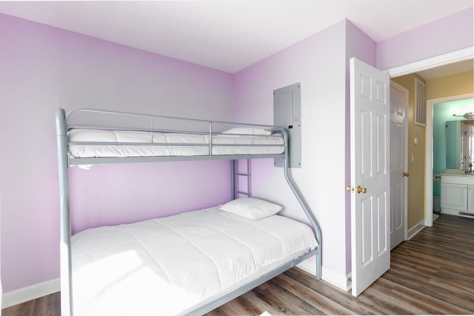 Purple walls and white bedding offer a soothing vibe