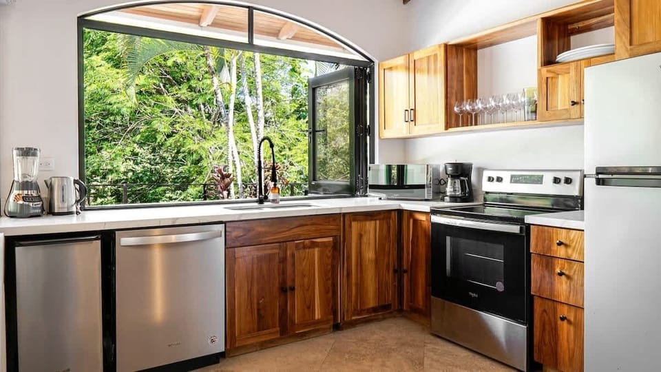 Fully stocked kitchen with accordion windows leading out to the patio terrace and bar, perfect breeze while cooking. 