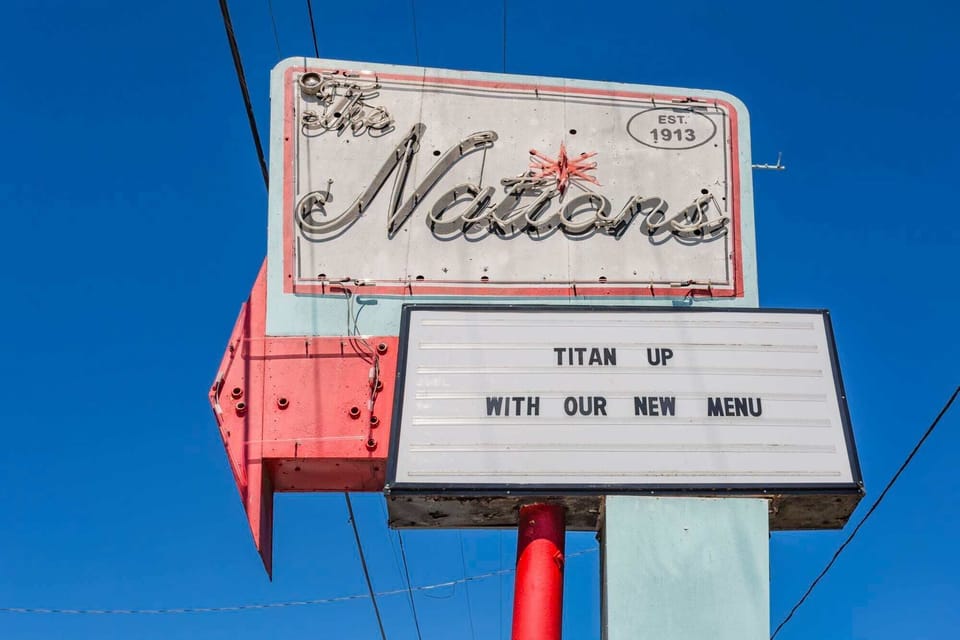 Nations neighborhood pole sign against blue sky