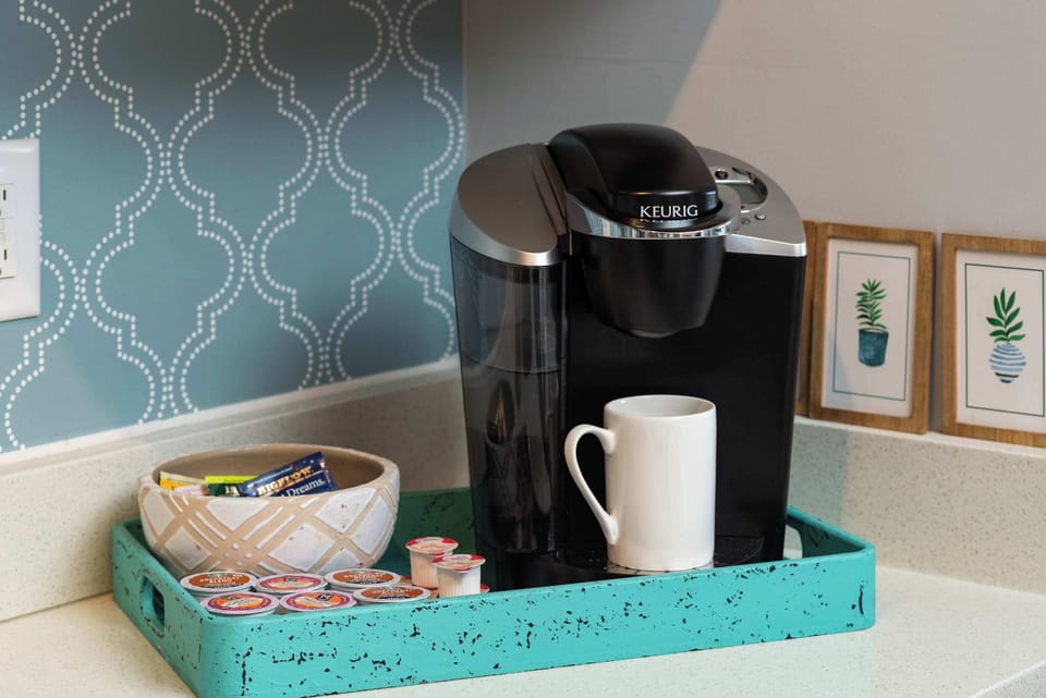 Coffee station with tray and mugs against blue wallpaper