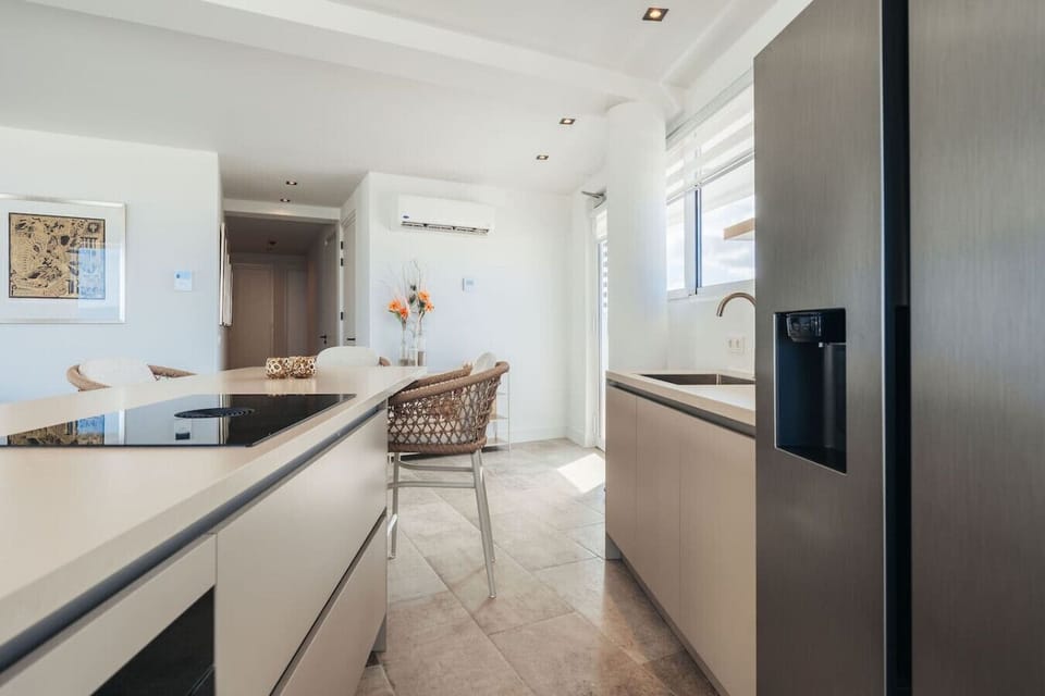 Gather around the kitchen island for a casual meal in this bright, open-concept space, where modern finishes meet breathtaking ocean views just beyond the glass.