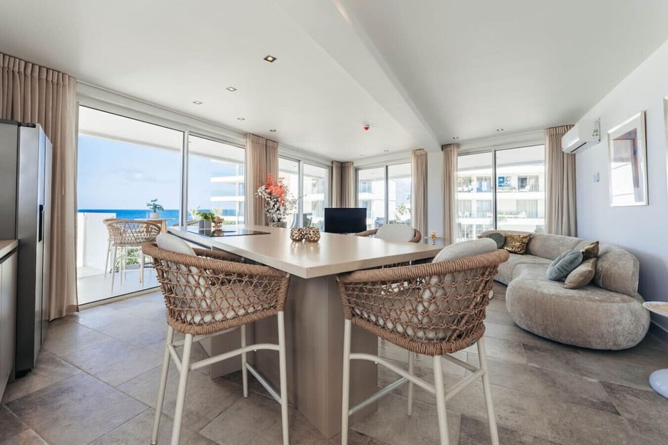 Where indoor elegance meets seaside serenity—this open-concept haven features a chic island bar, plush lounging, and walls of glass that frame endless ocean views.