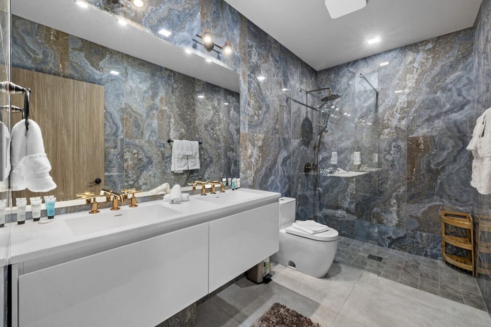 Start your day with a refreshing rainfall shower, then take your time at the double vanity—plenty of space to get ready, with fresh towels and essentials provided for a comfortable stay.