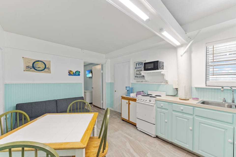 Your charming cottage kitchen features mint-green cabinets and coastal decor, creating a fresh seaside atmosphere for preparing memorable meals during your stay.