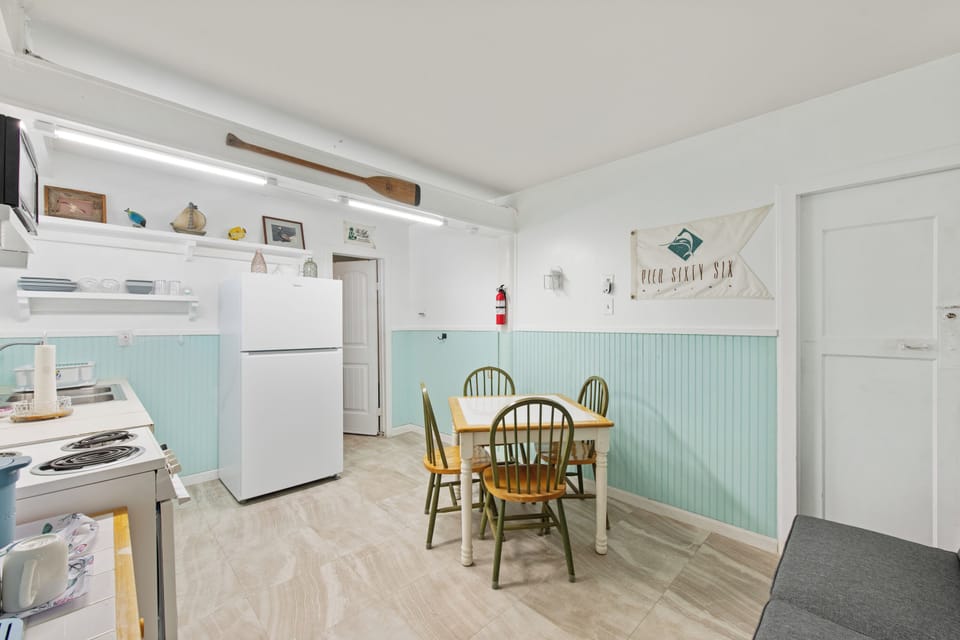 Your coastal-themed kitchen and dining nook features charming mint wainscoting, rustic beamed ceilings, and nautical touches that create the perfect seaside retreat atmosphere.