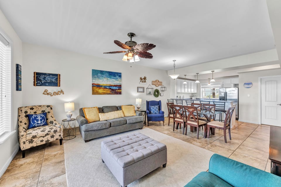 Relax in your spacious open-concept living area with coastal decor, comfortable seating, and a fully equipped kitchen for memorable vacation meals.
