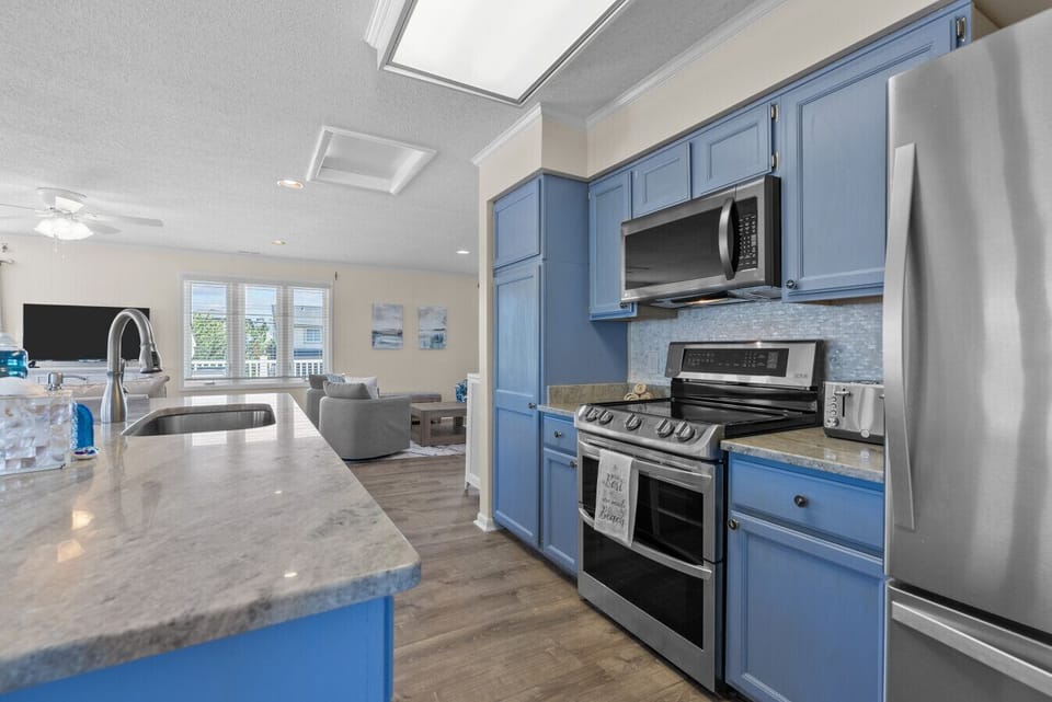 Stylish full kitchen with calming blue hues and modern appliances, where function meets charm.