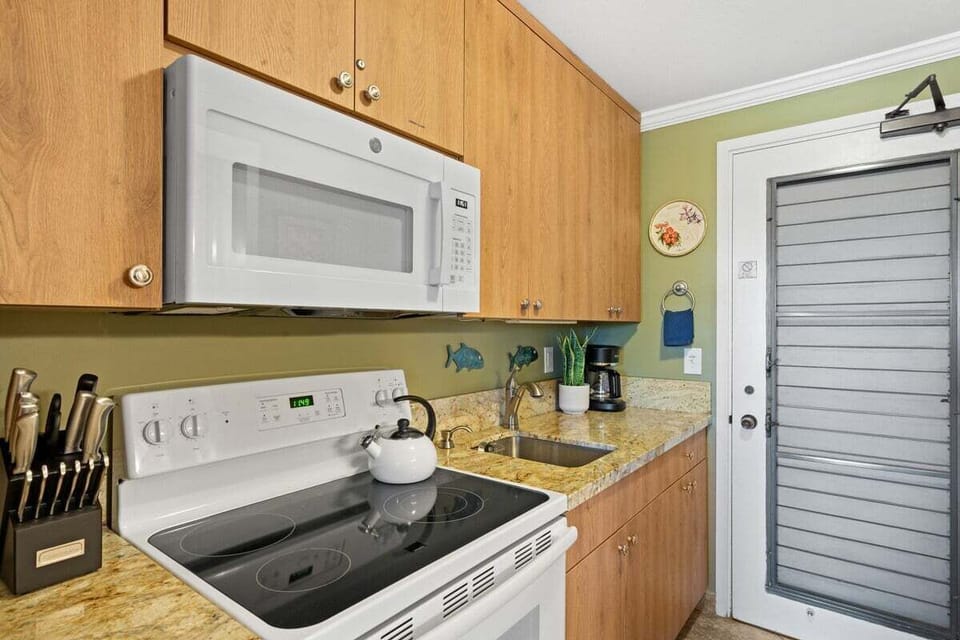 Functional studio kitchen with a smooth cooktop, microwave, and well‑organized essentials