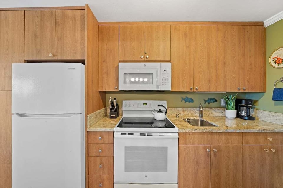 Fully equipped kitchen with warm wood cabinetry and white appliances