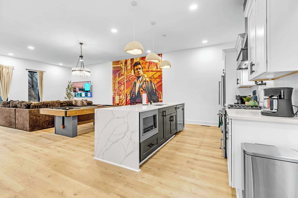 Open concept living room and kitchen mean the cook stays part of the party, pool table, mural wall, and sectional all in sight while you work