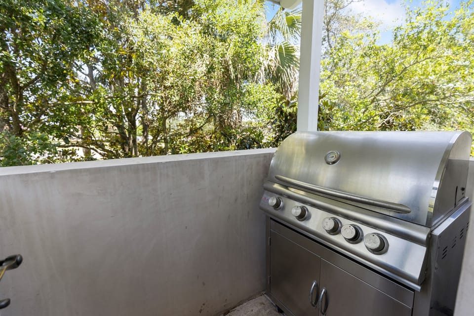 Fire up your outdoor culinary adventures with this premium stainless steel grill on your private covered patio, surrounded by lush tropical greenery.