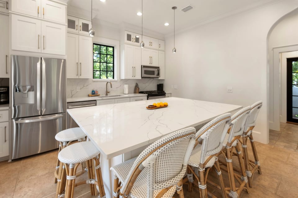 You'll love cooking in this stunning white kitchen with marble countertops and spacious island seating for memorable meals together.