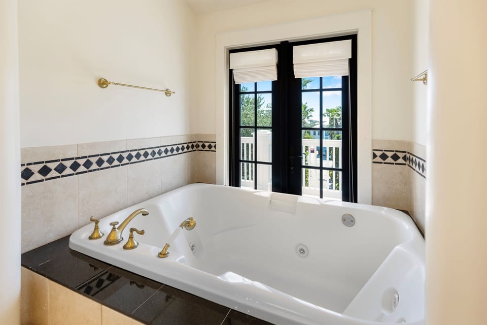 Unwind in your private jetted tub with elegant tilework and peaceful garden views through French doors.