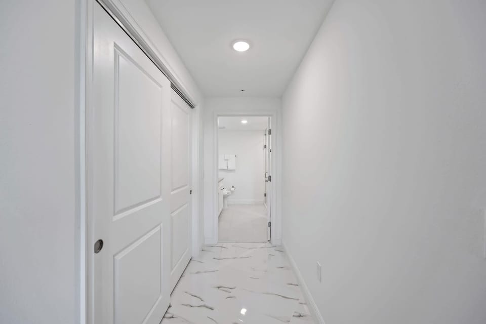 hallway with marble tile flooring leading to a bathroom