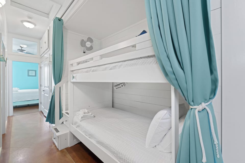 Hallway Alcove Offers Twin Bunk Beds with teal curtains and fans for each bunk providing convenience and personal space