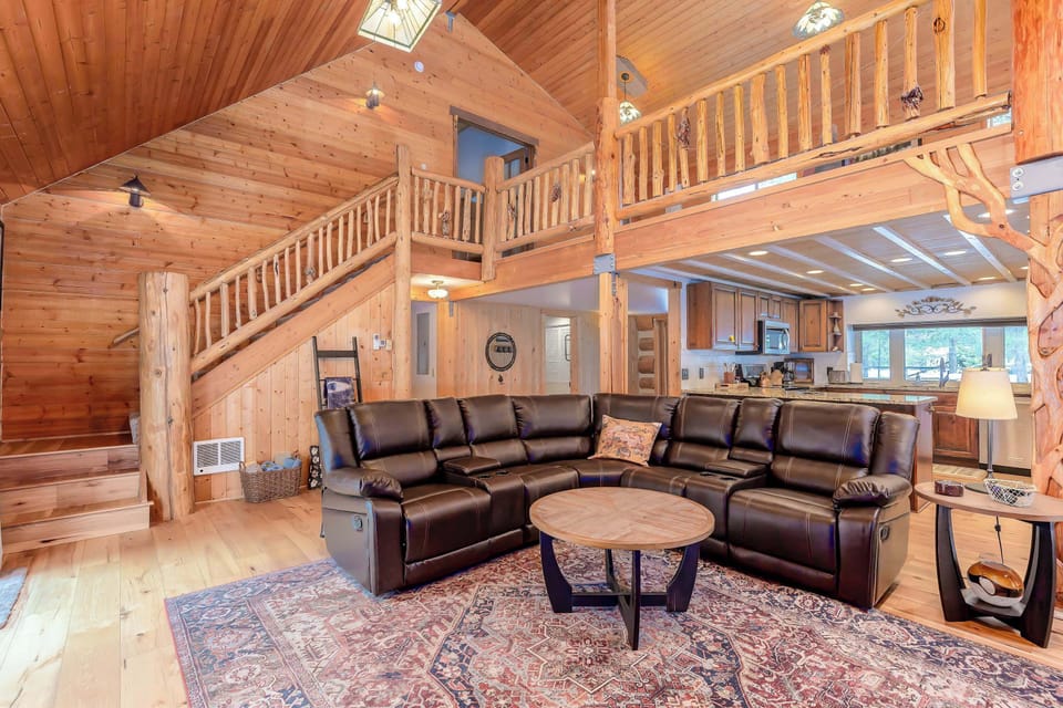 The beautifully furnished living room boasts large windows that let in natural light and showcase stunning views of the surrounding forest.