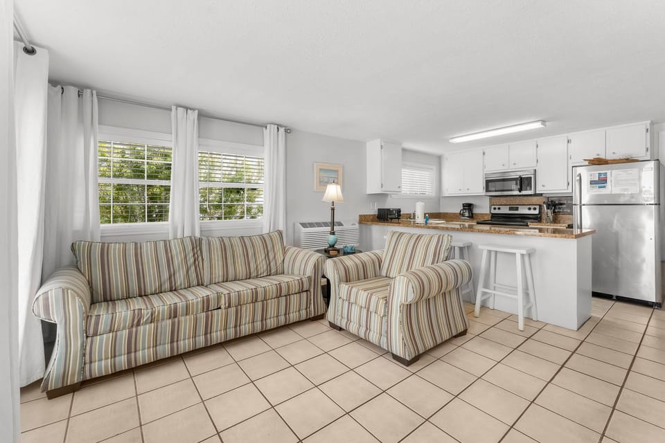 Bright living area with striped seating and an open kitchen featuring modern appliances.