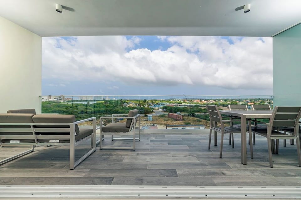 Stylish covered terrace with modern outdoor furniture and panoramic views of the surrounding neighborhood and distant ocean horizon.