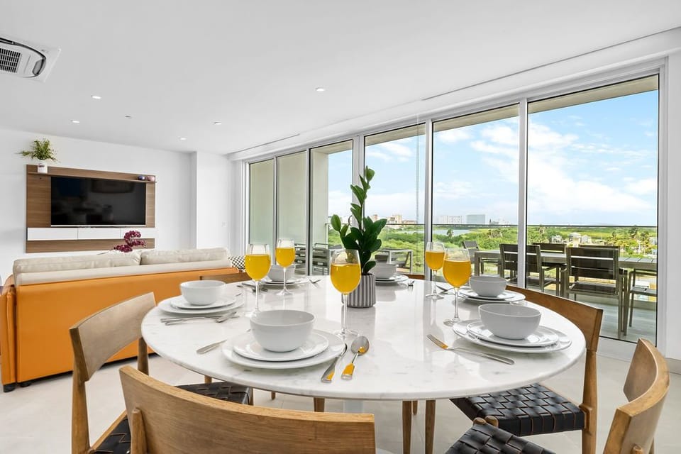 Start your day at this sunlit table with fresh juice and coffee, as natural light pours through expansive windows framing your private terrace and sweeping views beyond.