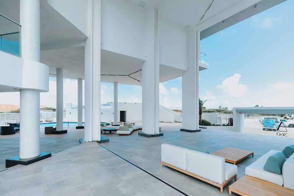 Contemporary open-air lounge framed by striking white columns, where you'll unwind on sleek seating while soaking in turquoise ocean views and refreshing sea breezes.