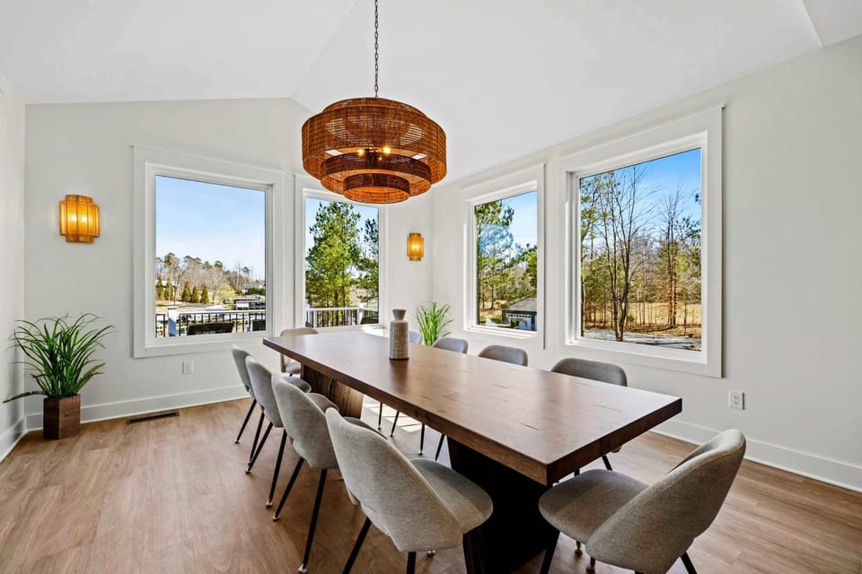 Dining Room - A long walnut table seats ten under a woven drum chandelier, framed by a wall of windows with the kitchen just steps away.