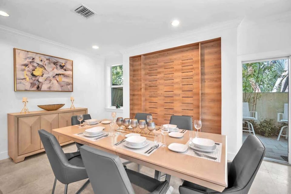 Dine in style in this elegant space, featuring a chic wood-accent wall, modern seating, and a beautifully set table. Perfect for shared meals and great conversation, this cozy setting blends warmth and sophistication with a lovely view.