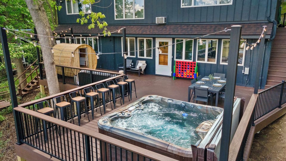 Large deck overlooking the Rock River with a hot tub, dining table, suana, and plenty of seating options.