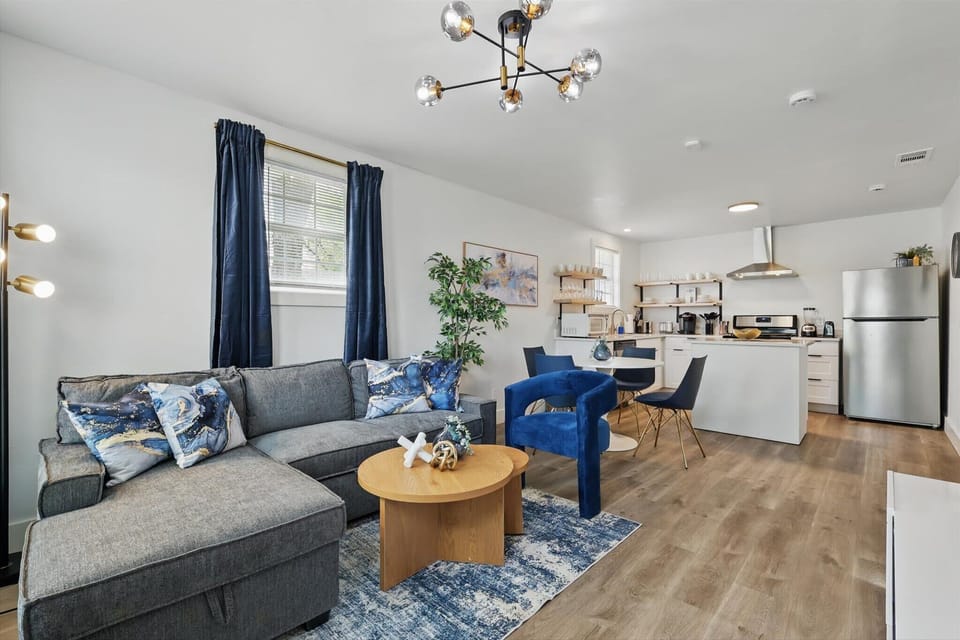 Sit back and relax! This spacious open-concept living room features plenty of natural light, decorative greenery, a wall-mounted TV, and comfortable seating.