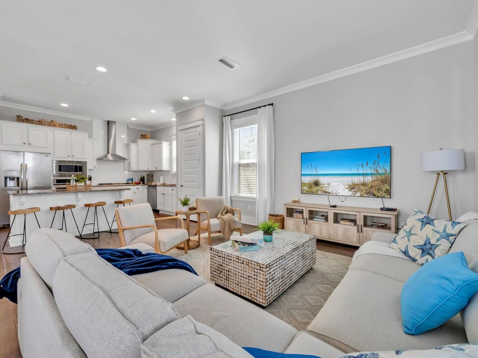 Settle into your bright, coastal-inspired living room where modern comfort meets beach vibes. The open layout flows to your fully-equipped kitchen.