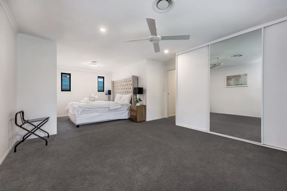 A spacious King Size Bedroom with Wardrobe, with portable fan and ceiling fan.