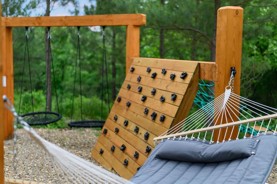 Family-friendly outdoor play area with rock wall, spider net, hammocks, and swings—endless fun for kids of all ages.