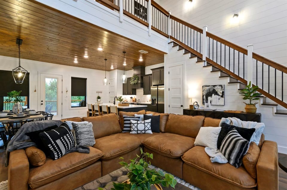 Bright open-concept living room with vaulted ceilings, crystal-rock fireplace, and panoramic forest views—ideal for family gatherings and cozy evenings.
