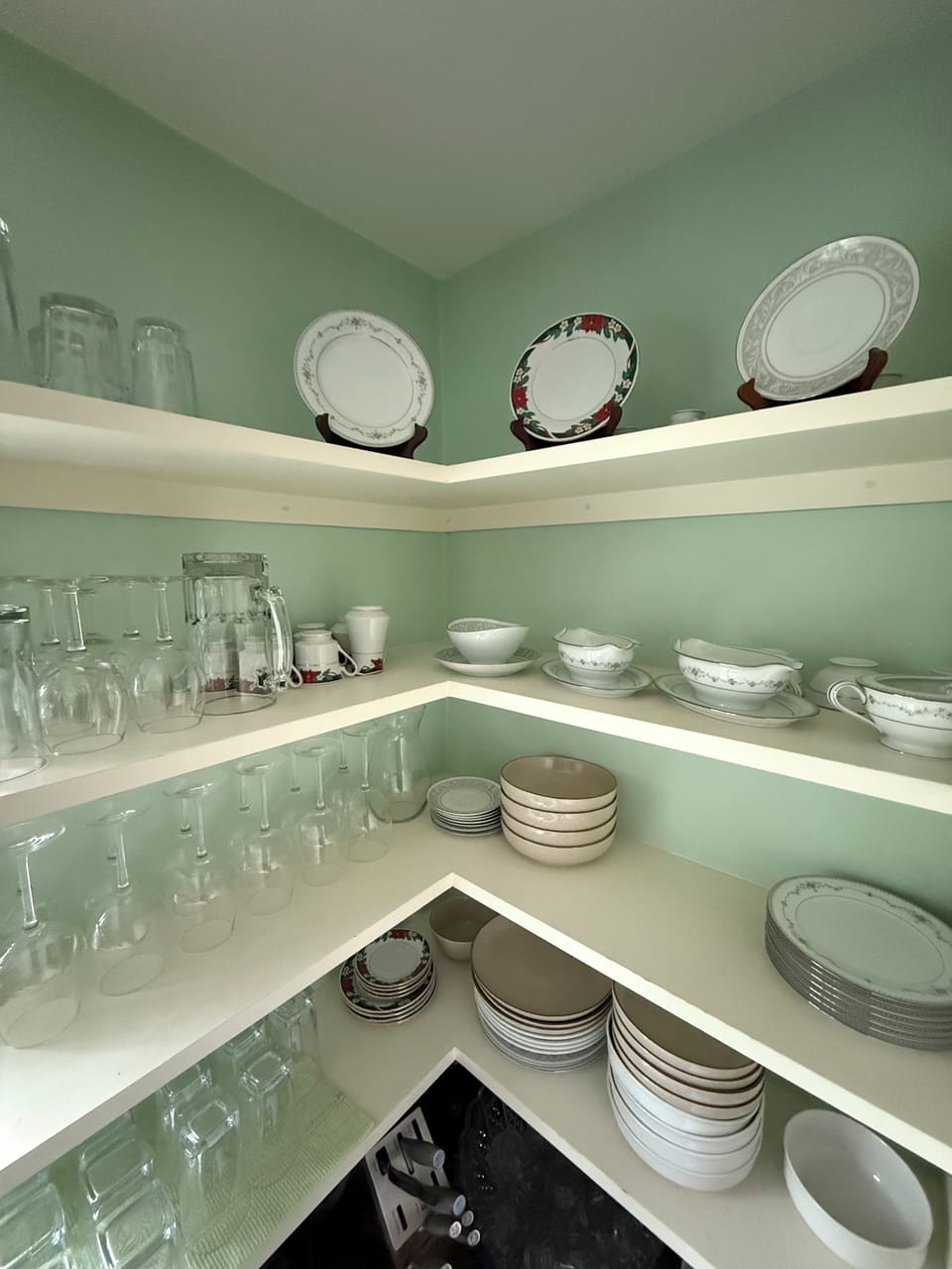 Kitchen shelf with wine glasses, plates, and bowls for everyday use.