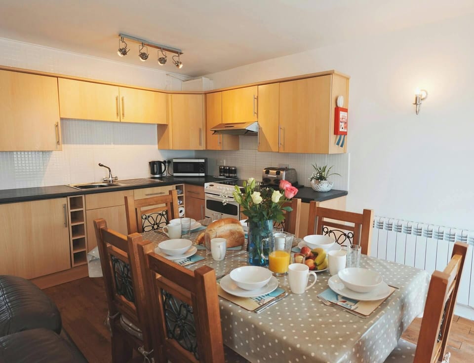 Wooden kitchen with dining table set for six and flowers in a vase