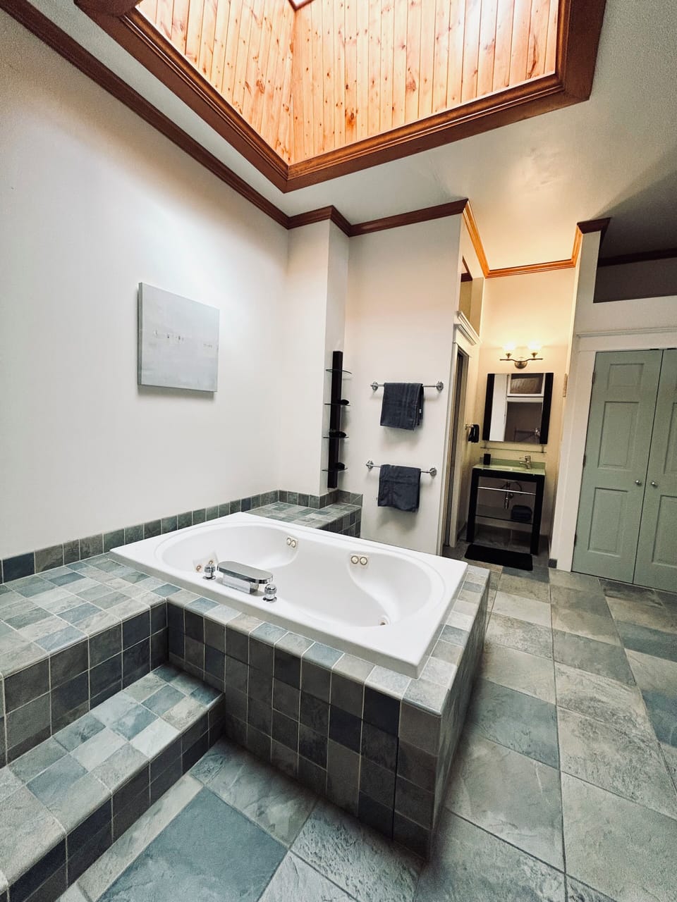 Bathroom with a jacuzzi tub positioned under a skylight. 