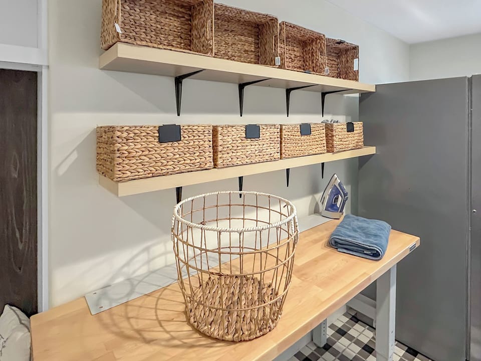 Neatly organized folding station with wicker baskets and a stylish wire hamper.