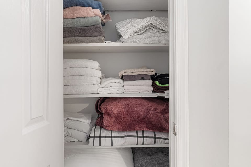 Fully stocked linen closet with extra towels, blankets, and bedding.
