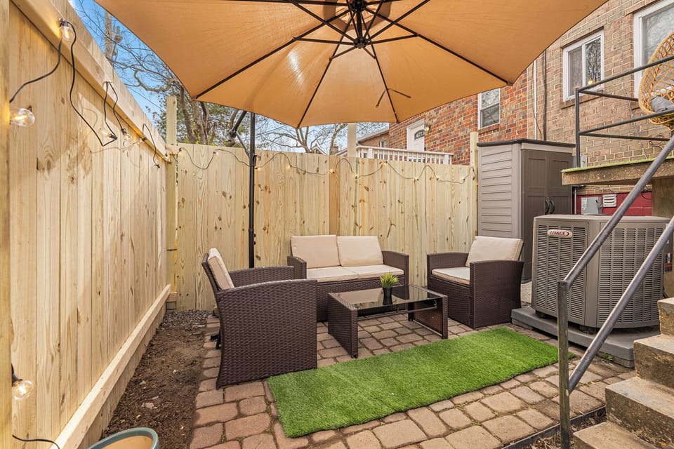 private outdoor retreat featuring cozy wicker seating, a large umbrella.