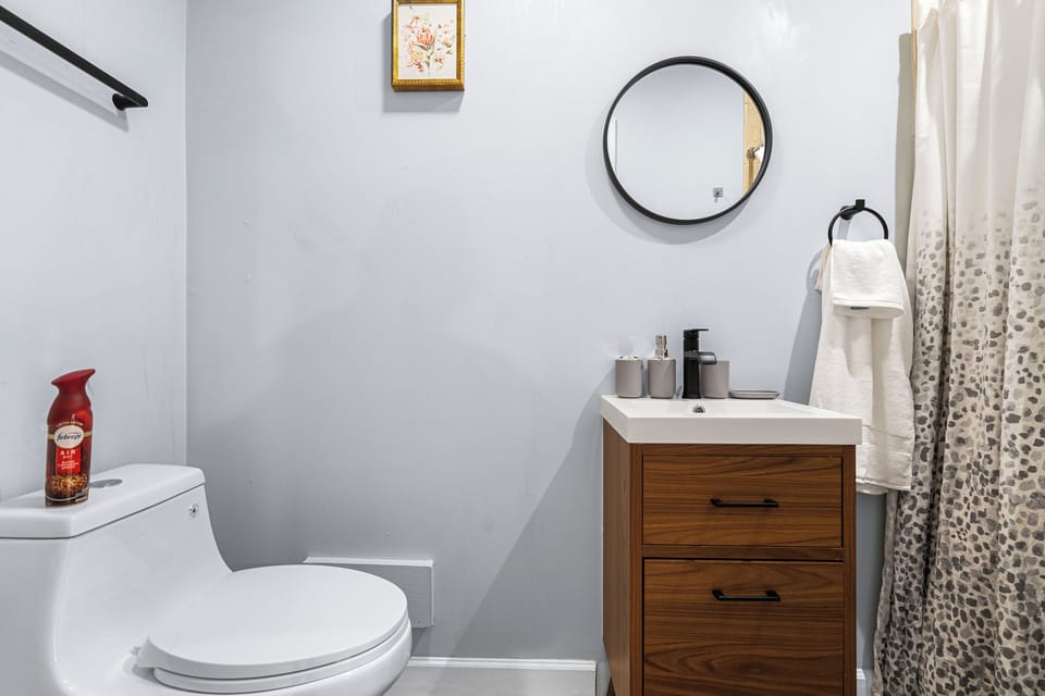 Cozy full bathroom with a sleek modern vanity, rainfall shower and plush towels.