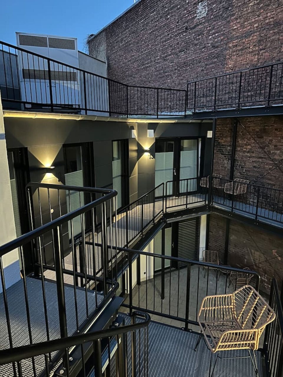 Ein modernes Hofensemble mit industriellem Charme – geschwungene Metalltreppen und stilvolle Balkone verbinden die Apartments auf mehreren Ebenen und schaffen eine besondere Atmosphäre.