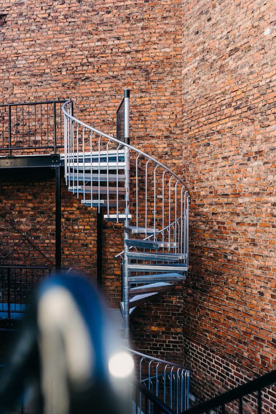 Industrieller Charme trifft auf modernes Design: Die elegante Wendeltreppe fügt sich perfekt in das historische Backsteinambiente ein und verbindet die Etagen dieses einzigartigen Wohnkonzepts.