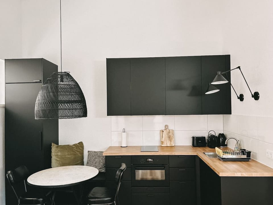 Stil trifft Funktionalität! Diese moderne Küche mit dunklen Fronten, Holzarbeitsplatte und Designlampen bietet die perfekte Umgebung für kulinarische Erlebnisse. Genieße stilvolle Dinnerabende in deinem urbanen Rückzugsort!