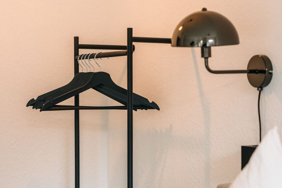 Stylisch und praktisch: Der minimalistische Kleiderständer sorgt für Ordnung und bietet Platz für deine Lieblingsoutfits. Perfekt ausgeleuchtet durch die elegante Wandlampe – hier beginnt dein Aufenthalt mit Stil.