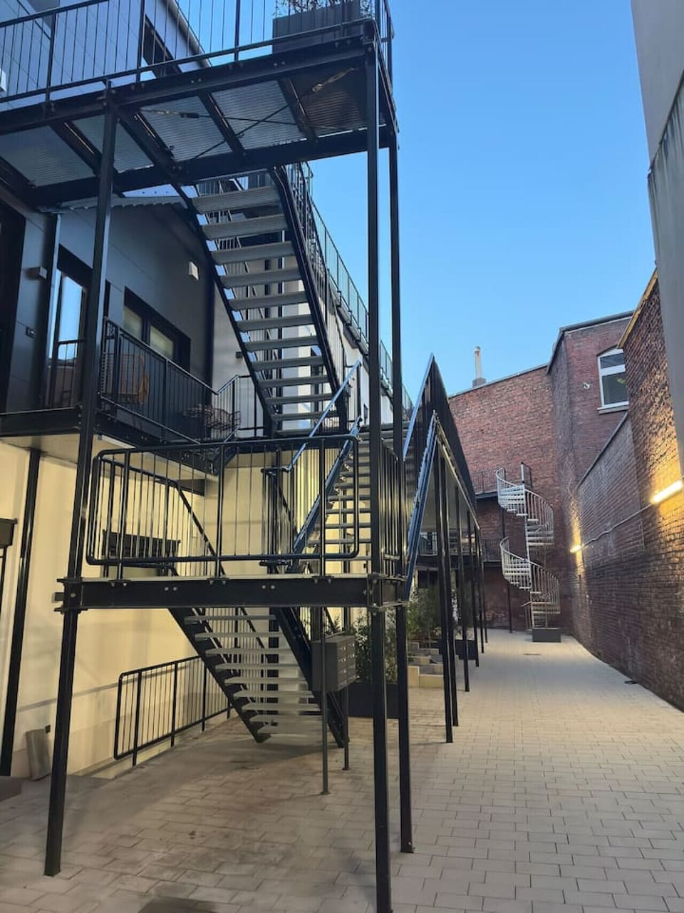 Moderner Industriecharme trifft auf urbanes Design – dieser stilvolle Innenhof mit seinen markanten Stahltreppen verbindet historische Backsteinarchitektur mit zeitgemäßem Wohnen in einer einzigartigen Atmosphäre
