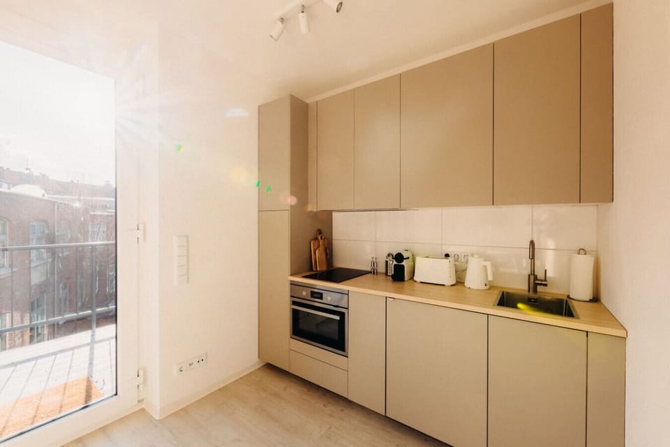 Die Morgensonne flutet diese stilvolle Küche mit warmem Licht und schafft eine Atmosphäre zum Wohlfühlen. Mit modernen Geräten und cleverem Stauraum ist sie der perfekte Ort für ein gemütliches Frühstück mit Blick über die Stadt.