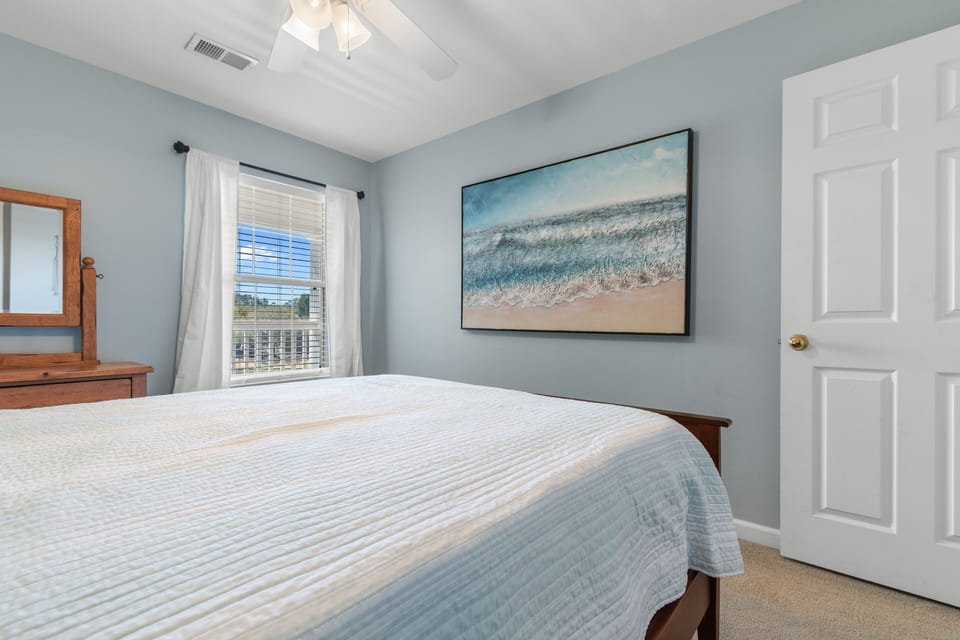 Drift off in this serene bedroom where soft blue walls and ocean artwork create your personal coastal retreat.