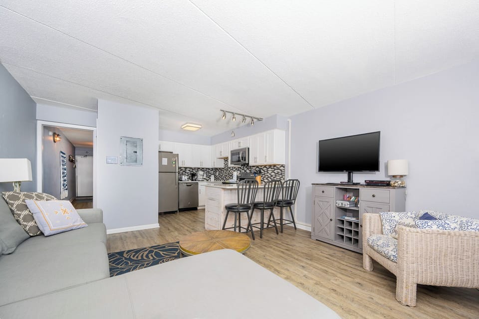 The living area features a cozy sofa, a stylish TV, and a modern kitchen with sleek appliances, perfect for relaxation
